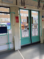 Inside of a tram with closed doors and view of the street outside. Public transport, travel, and daily commuting in the city.