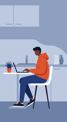 Young man working remotely on a laptop in a modern kitchen setting. Ideal for themes of home office, flexible work, and digital lifestyle.