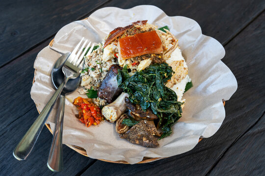Traditional Balinese roast pork dish,babi guling Pande Egi, Gianyar, Bali Indonesia,served with rice, vegetables, chili, and crispy pork skin on a bamboo basket.