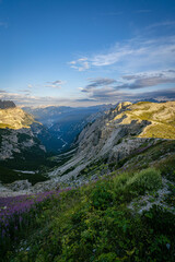 Obraz premium Dolomites mountain panorama with Cadini di Misurina rocky towers and green alpine ridges lit by warm evening sunlight