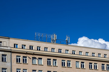 Modern cellular antennas on an urban building rooftop provide essential wireless communication infrastructure against a clear blue sky