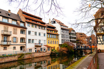 The charming canals of Colmar showcase festive lights during Christmas as locals stroll along the riverside. The historic buildings create a picturesque atmosphere.