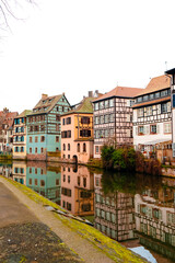 Colmar river reflects beautifully colored old buildings during Christmas, creating a festive ambiance. The city's unique architecture adds to the seasonal charm.
