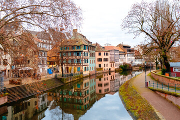 Colmar charming riverbanks showcase colorful architecture adorned with festive decorations. The reflection creates a picturesque holiday atmosphere in the city.