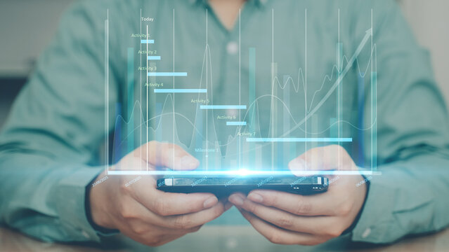 Businessman holding smartphone with holographic financial graph. Concept of digital finance, stock market, big data analytics, and modern business technology.