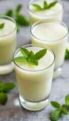 Refreshing creamy green smoothie with fresh mint leaves in clear glasses on a textured background
