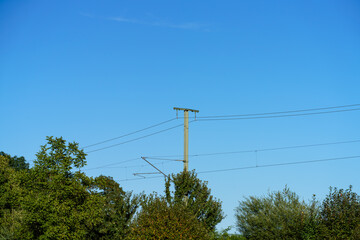 Obraz premium Power lines stretch across a clear blue sky in a rural area during the day