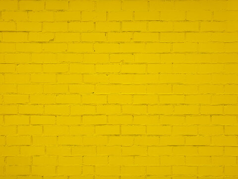 Textured yellow brick wall with uneven surface. Rough and grunge texture. Brick painted with yellow paint. Uneven, sloppy brickwork