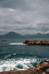 Man Standing on Coastal Rocks by the Sea in the Faroe Islands