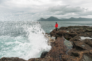 Man Standing on Coastal Rocks by the Sea in the Faroe Islands