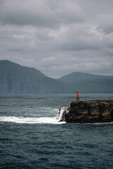 Man Standing on Coastal Rocks by the Sea in the Faroe Islands