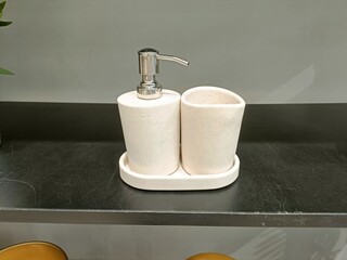 Stylish bathroom accessories set featuring liquid dispenser and cup on a countertop in a modern setting
