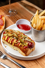 Delicious hot dog served with fries. A tasty hot dog topped with mustard and onions is served alongside crispy fries and ketchup in a casual setting.