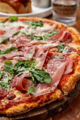 Tasty pizza with meats and greens. A mouthwatering pizza features layers of cured meats and fresh greens, creating an appetizing dish perfect for sharing.