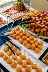 Tasty appetizers at buffet. Various appetizers are arranged attractively at a buffet, featuring fried treats, meats, and decorative fruits.
