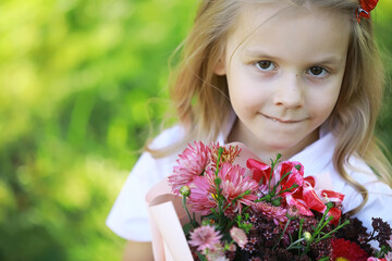 Fototapeta premium Smiling Girl Holding a Bouquet of Colorful Flowers in a Garden on a Bright Summer Day
