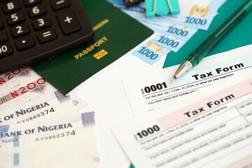 Nigerian naira money bills and calculator with tax form on flag. Taxation and accounting concept