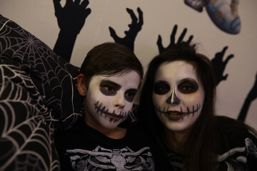 Mother and Child in Skeleton Halloween Costumes with Face Paint and Spiderweb Decorations