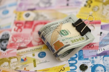Philippines peso currency money bills and bunch of us dollar banknotes. The concept of economics and currency exchange