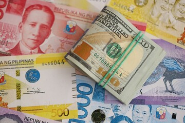 Philippines peso currency money bills and bunch of us dollar banknotes. The concept of economics and currency exchange