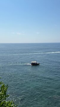 A small pleasure boat with tourists sails along the shore.