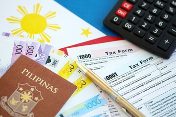 Philippines peso money bills and calculator with tax form on flag. Taxation and accounting concept