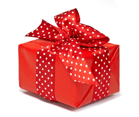 Prezent zapakowany w czerwony papier z czerwoną wstążką w białe groszki na białym tle