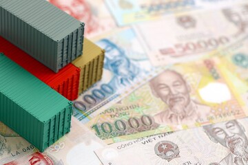 Vietnamese dong currency money bills and toy cargo containers. The concept of shipping and logistics