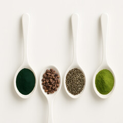 Assorted superfood powders and seeds in white ceramic spoons on light background healthy nutrition concept