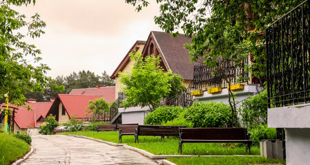 Residential street lined with trees and benches in a tranquil countryside setting during overcast weather