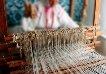 Crafting intricate textiles at a traditional loom in a cozy workshop during the daylight hours