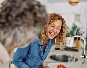 Portrait of happy senior mid aged mature couple prepering meal with fresh vegatebles in kitchen at hpme