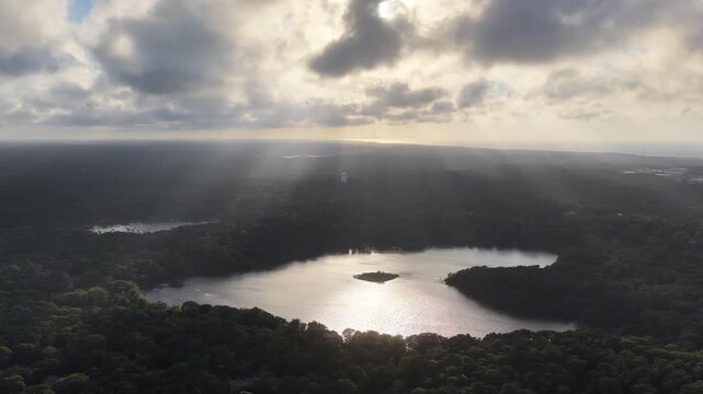 Beams of sunlight fall through low clouds illuminating Pilgrim Lake in Orleans on Cape Cod. This scenic Massachusetts peninsula harbors many ponds and lakes left over from the last glacial period.