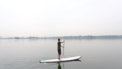 54 year old Brazilian man sailing with a standup paddleboard in the Guarapiranga dam in the city of Sao Paulo.