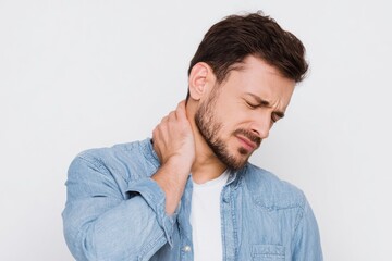 Obraz premium A man with a beard grimaces clutching his neck in apparent pain set against a plain white background