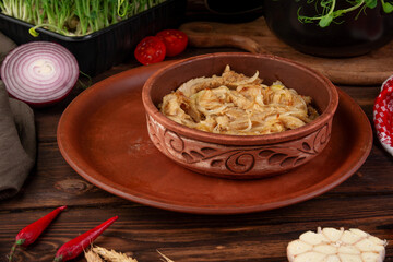 Tender braised tripe cooked with onion and spices served in rustic clay bowl on wooden table authentic homemade dish