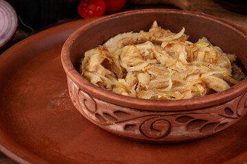 Tender braised tripe cooked with onion and spices served in rustic clay bowl on wooden table authentic homemade dish