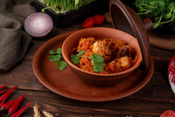Hearty traditional stewed meat with cabbage carrots and spices served in clay pot garnished with fresh parsley on wooden table