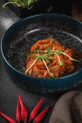 Traditional stewed cabbage in tomato sauce with fresh herbs served in dark ceramic bowl on rustic table