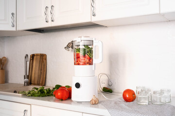 A beautifully designed and stylish kitchen setting showcasing a vibrant blender with a variety of fresh ingredients gathered fresh tomatoes and green pepper, basil, garlic for sause.
