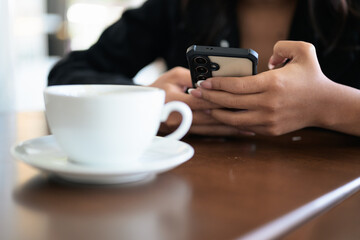 Close-up of woman hands texting and chatting using mobile phone indoors in coffee shop restaurant