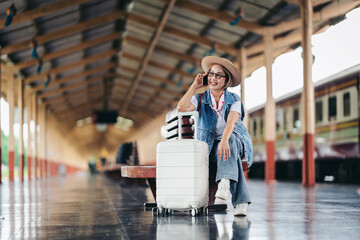 Fototapeta premium Asian adult woman traveler happy talking phone train station platform travel journey adventure suitcase