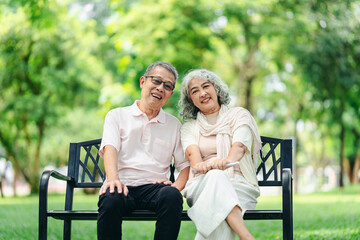 Naklejka premium Joyful older senior couple happy smiling relaxing on park bench enjoying nature outdoors embracing their healthy retirement lifestyle and beautiful golden years