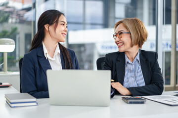 Two Businesswomen Discussing Data Analysis on Laptop for Business Strategy and Career Growth In Modern Office Workplace Professional Smiling