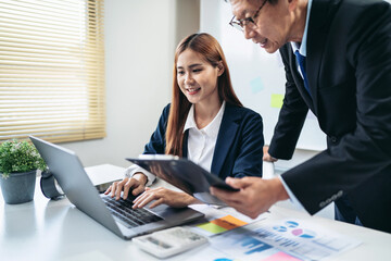 A woman and a man are working together on a laptop