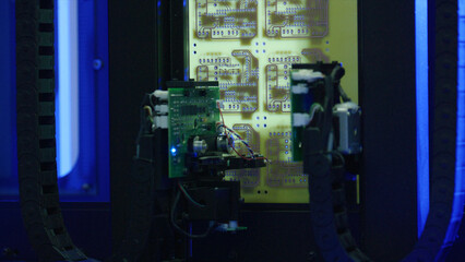 Automated robotic arms precisely placing and soldering components onto a circuit board in a blue lit, advanced manufacturing facility highlight the precision of modern electronics production