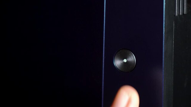 Close-Up of Finger Pressing Glowing Power Button to Start Electronic Device