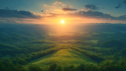 鮮やかな日の出が丘陵地の緑の木々の上空を照らす壮大なシーン