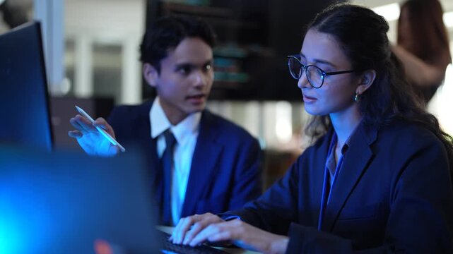 A female software developer mentors a junior programmer, conducting a live code review. They are pair programming to debug an application's frontend script in a tech startup.
