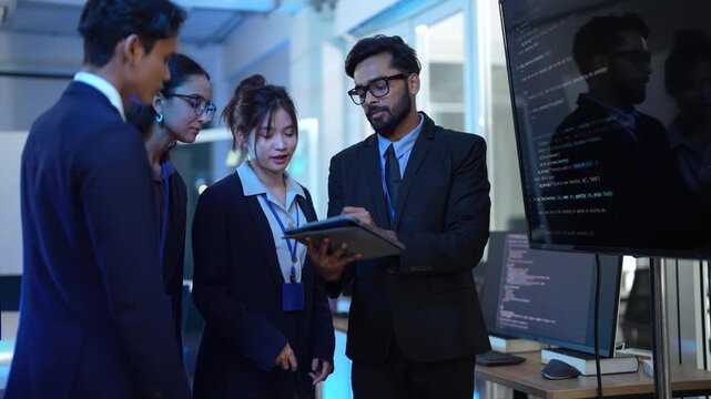 A project lead facilitates a daily scrum meeting, reviewing the sprint backlog and user stories on a tablet with his team of software developers in a modern tech hub office.